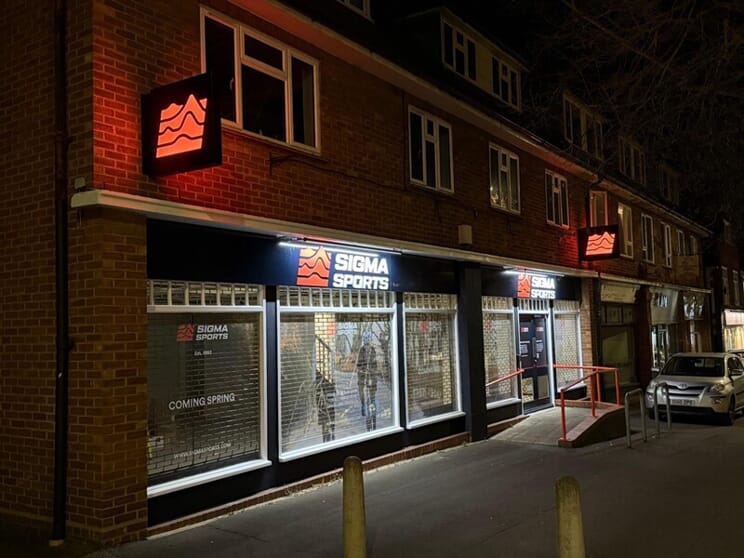 An image of the Sigma Sports exterior signage lit up at night.